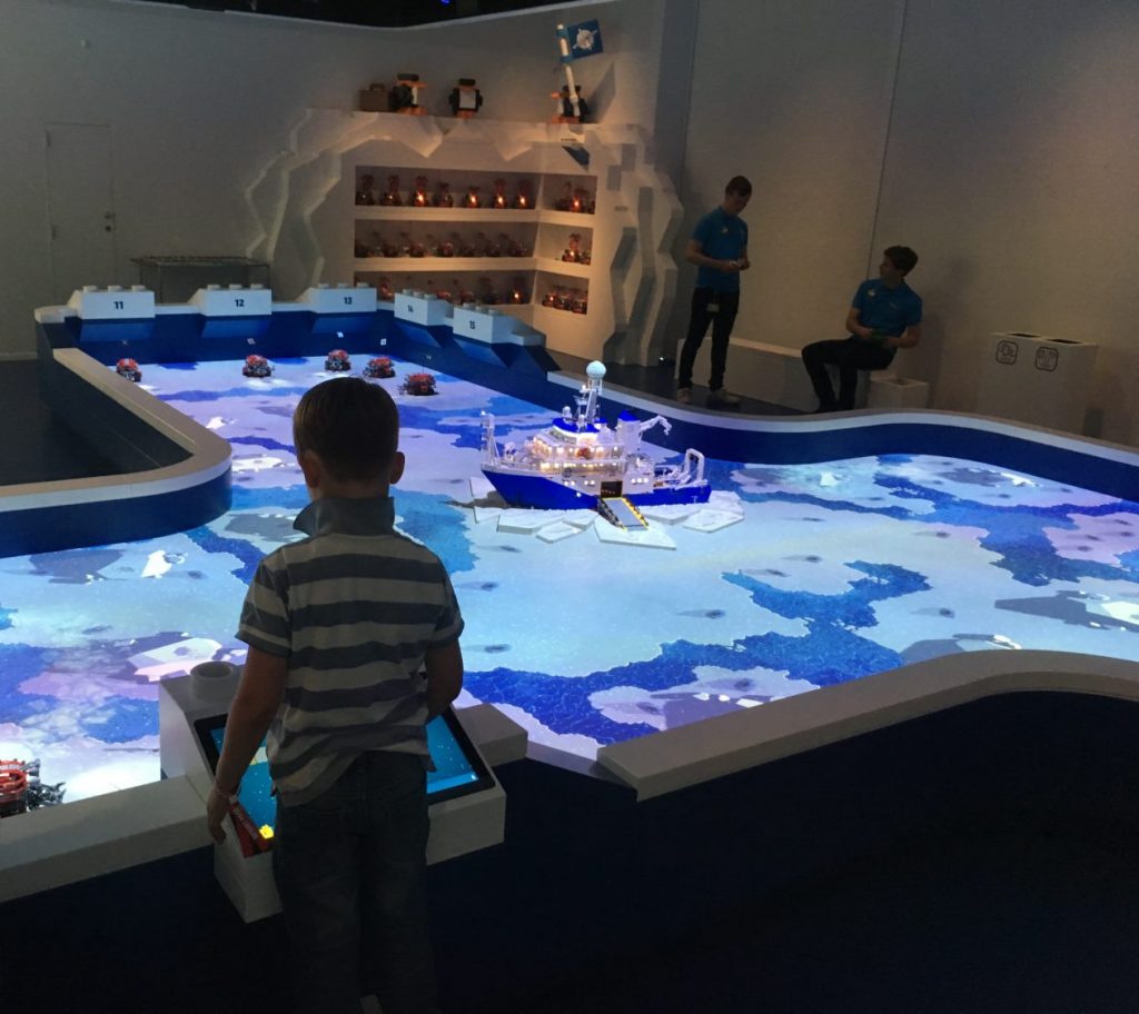 A large blue sea map of lego which has moving lego boats controlled by children and adults. 
