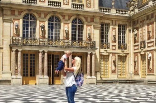 woman holding a baby in front of Versailles palace